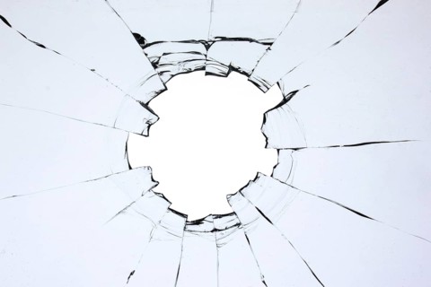 Hole in the glass, broken window with cracks texture. Effect of broken transparent glass