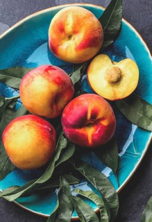 Food, Fresh ripe peach with peach tree leaves on blue plate, top view