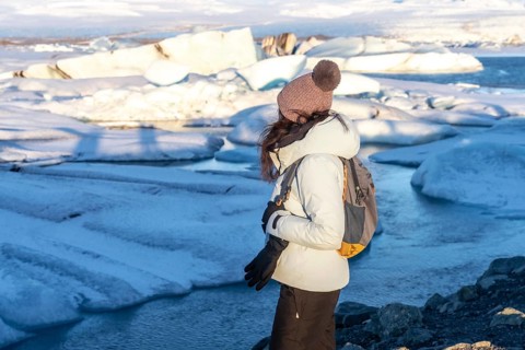 A woman with her back turned looking at the frozen iceberg lake of Jokursarlon. Iceland