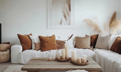 Scandinavian living room with white walls, wooden floor, autumn-themed cushions and candles on the