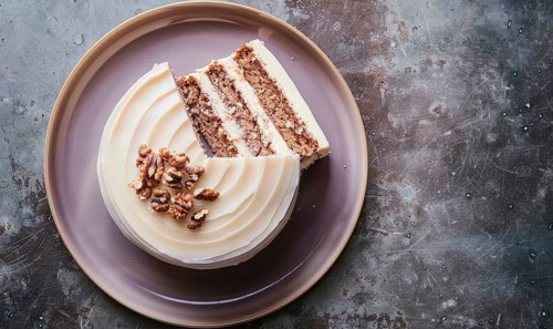 Fig and walnut cake with cream cheese frosting on a muted purple plate AI generated