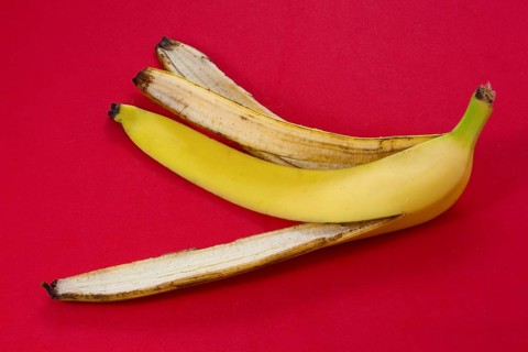 Banana peel skin lies on a red background. Organic fruit residues after cleaning