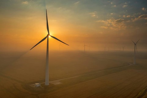 Beautiful aerial sunset landscape with windmills or wind turbine on wind farm in rotation to