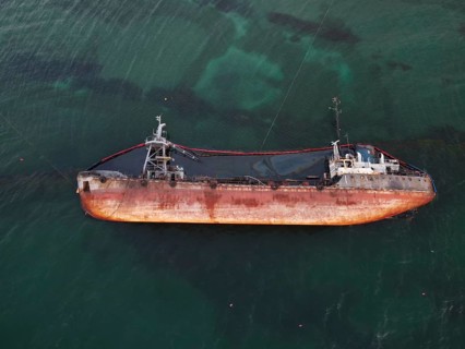 Top view of an old tanker that ran aground, overturned and polluted the coast with oil spilled from
