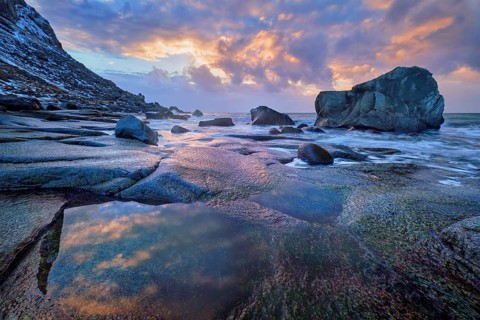 Rocks on beach of fjord of Norwegian sea in winter on sunset. Utakliev beach, Lofoten islands,