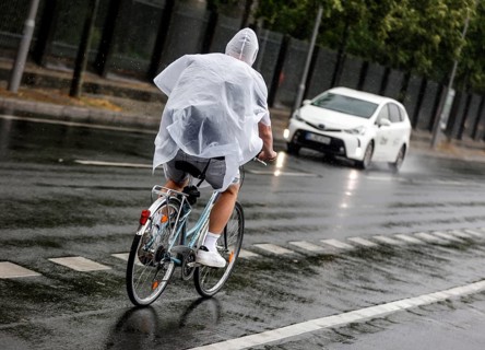 Bicycle rider with rain cape in heavy rain, Berlin, 23.06.2023
