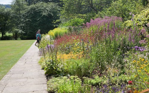 People enjoying summer flower borders in the botanical gardens at Bath, north east Somerset,