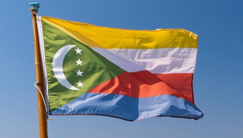 The flag of the Comoros flutters in the wind, isolated against a blue sky