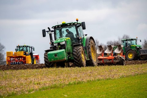 Tractor with a plough preparing the soil of a field for planting, Agriculture, Spring