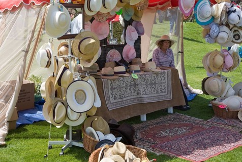 Woman selling hats from tent stall during garden event at Helmingham Hall, Suffolk, England, United