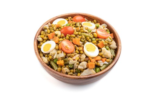 Mung bean porridge with quail eggs, tomatoes and vegetables isolated on white background. Side