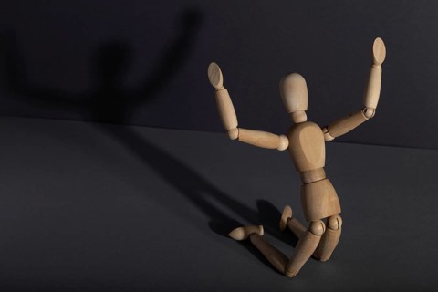 Wooden mannequin in imploration, praying position on gray background. religion, despair concept.