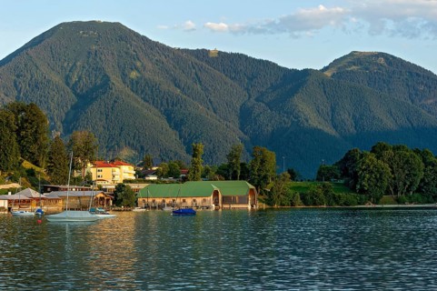 Tegernsee with sailing boats and boat huts, warm evening light, town Tegernsee, mountain Wallberg,