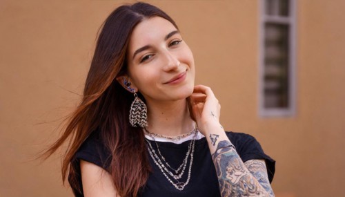 Smiling young woman with dark hair and visible tattoos poses relaxed, AI generated, AI generated