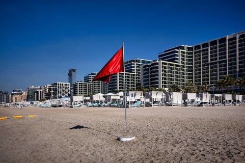 Red flag, swimming prohibited, on the beach in front of Hotel Marriot Resort Palm Jumeirah, behind