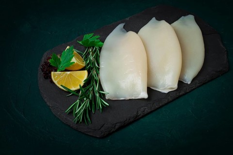 Fresh squid body, raw, three carcasses, top view, on black slate, no people