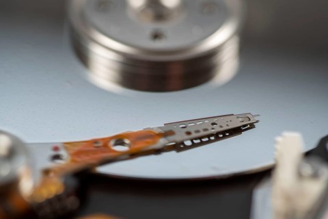 Computer hard drive, opened, read/write head on the storage disc. Symbol image