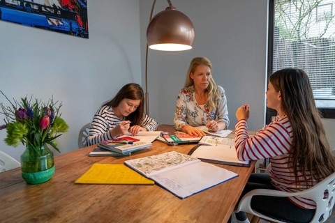 Homeschooling, during the lockdown in January 2021, mother helps her two daughters, at home,