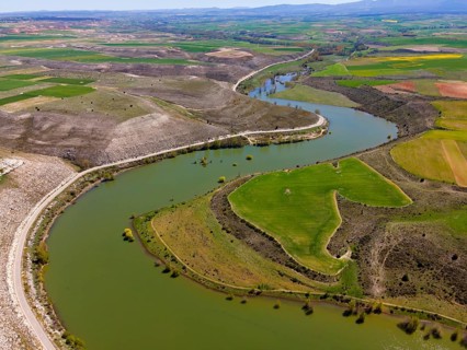 Aerial view of a river winding through a green, hilly landscape with fields, aerial view, near