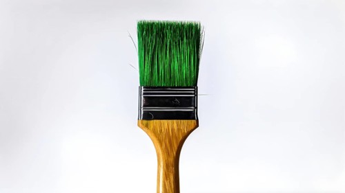 Thick paintbrush dipped in green bristles dripping onto a white background, AI generated