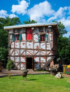 Traditional half-timbered house with bright red windows and red door, green windows and cradle,