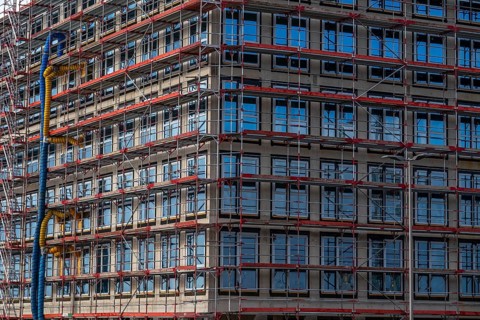Large construction site, scaffolded shell of an office building complex, air hoses for building