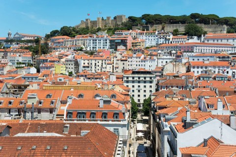 View over a city with many houses and red roofs, in the background a castle on a hill, viewpoint,