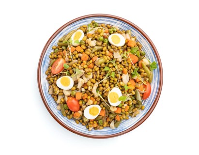 Mung bean porridge with quail eggs, tomatoes and microgreen sprouts isolated on a white background.