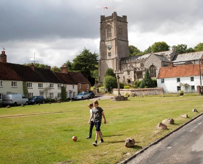 Church of St Michael and butter cross on the village green in Aldbourne, Wiltshire, England, UK