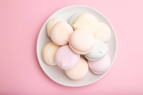 Colored zephyr or marshmallow on pastel pink background. Top view, close up