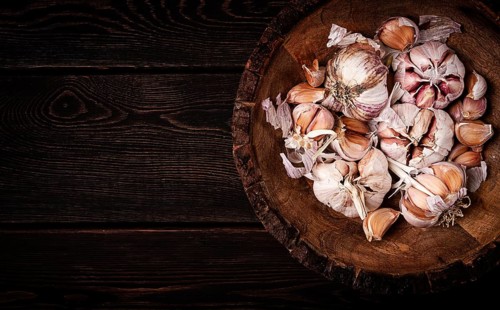 Fresh garlic, in a wooden plate, top view, close-up, no people