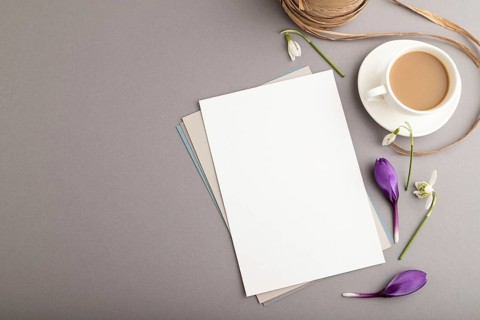 White paper sheet mockup with spring snowdrop crocus and galanthus flowers and cup of coffee on