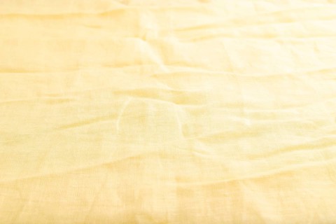 Fragment of smooth yellow linen tissue. Side view, natural textile background and texture
