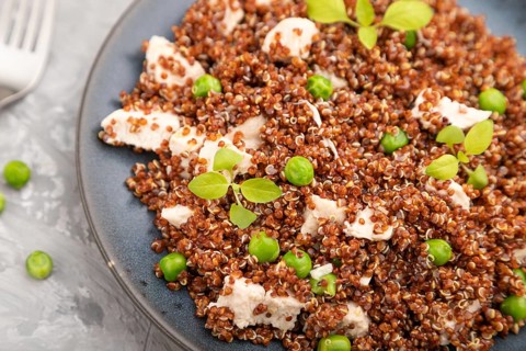 Quinoa porridge with green pea and chicken on ceramic plate on a gray concrete background and