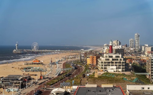 View over the beach of Scheveningen, the pier with Ferris wheel and the skyline of the town, which
