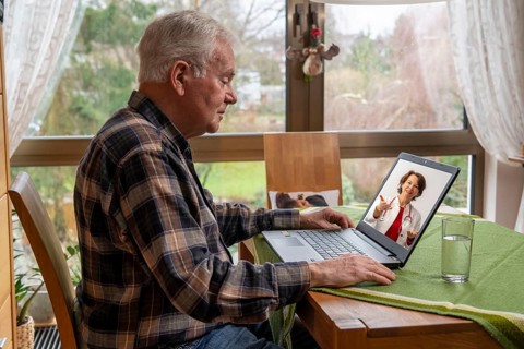 Symbolic image of telemedicine, elderly patient speaking to a doctor in a video conference from