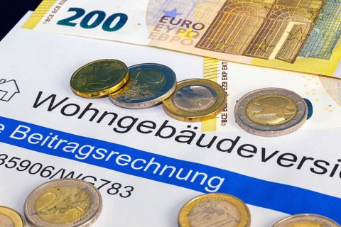 Symbolic image of building insurance: close-up of contract documents, a model house, euro banknotes