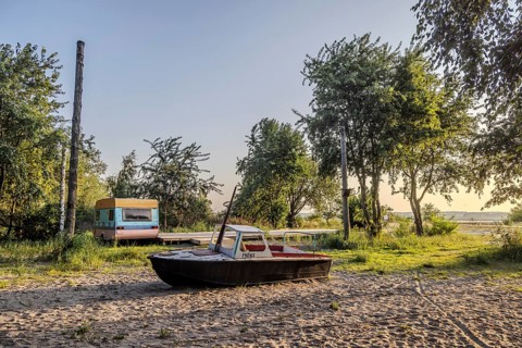 View of the natural beach with boat and old caravan. Peenemünde peninsula on the island of Usedom,