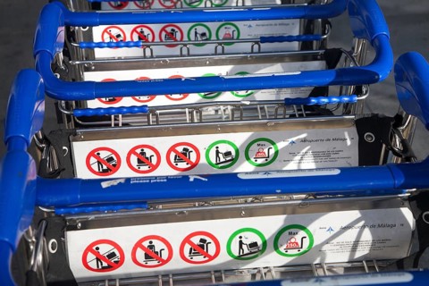 Close up of line of stacked luggage trolleys with rules about use, Malaga airport, Spain, Europe
