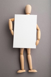 Wooden mannequin holding blank poster on gray pastel background. copy space, isolated, presentation