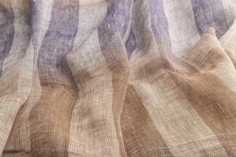 Fragment of brown and violet linen tissue. Side view, natural textile background and texture. wave