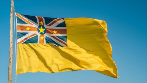 The flag of Niue, an island state in the Pacific Ocean, flutters in the wind, isolated against a