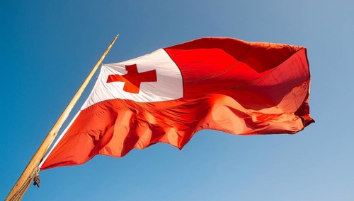 The flag of Tonga, Pacific island state, flutters in the wind, isolated against a blue sky