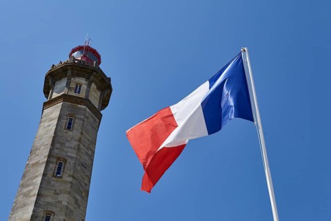 Spire of the Phare des Baleines and a waving French flag in Saint-Clément-des-Baleines, Département