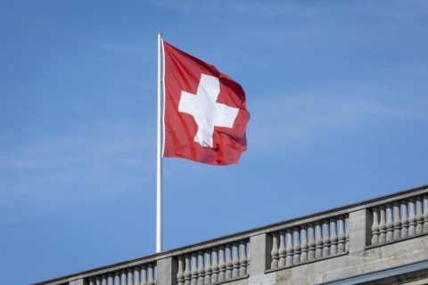 The Swiss flag flies against a blue sky on the roof of the Swiss Embassy in Berlin, 28 March 2024