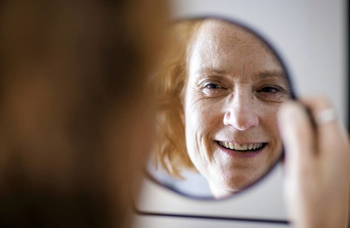 Symbol photo. A smiling elderly woman can be seen in a mirror. Berlin, 13.08.2024