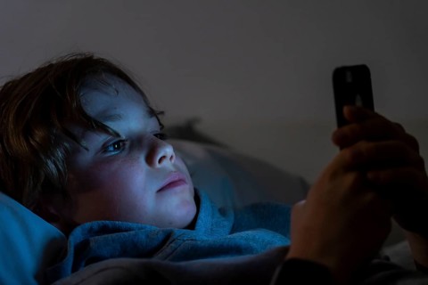 A boy plays computer games on a mobile phone, smartphone