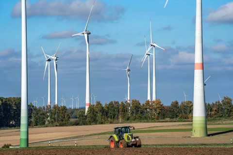 Farmer working in the fields, with a tractor, wind farm above the village of Lichtenau,