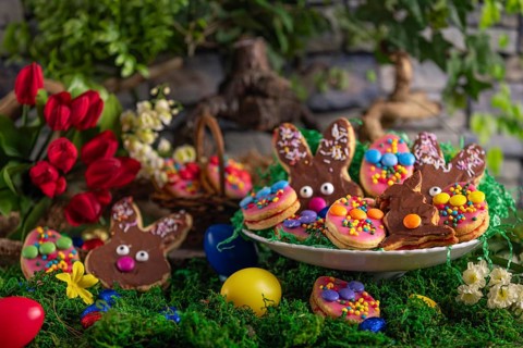 Colourful Easter biscuits with a bouquet of tulips and Easter eggs, arranged on a moss-covered