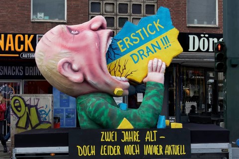 Vladimir Putin with his mouth open, devouring Ukraine, papier-mâché figure, satirical float by